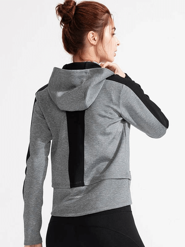 Back view of a woman wearing a gray hooded sweatshirt with thumb holes, perfect for workouts. Anti-shrink and quick-dry fabric.